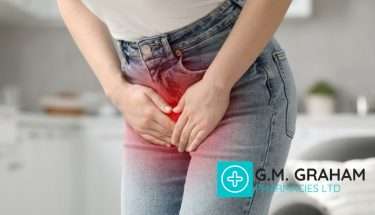 woman wearing white shirt and jeans clutching lower area in discomfort