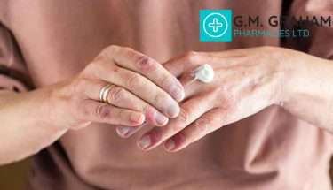 woman in pink shirt using eczema cream on hand